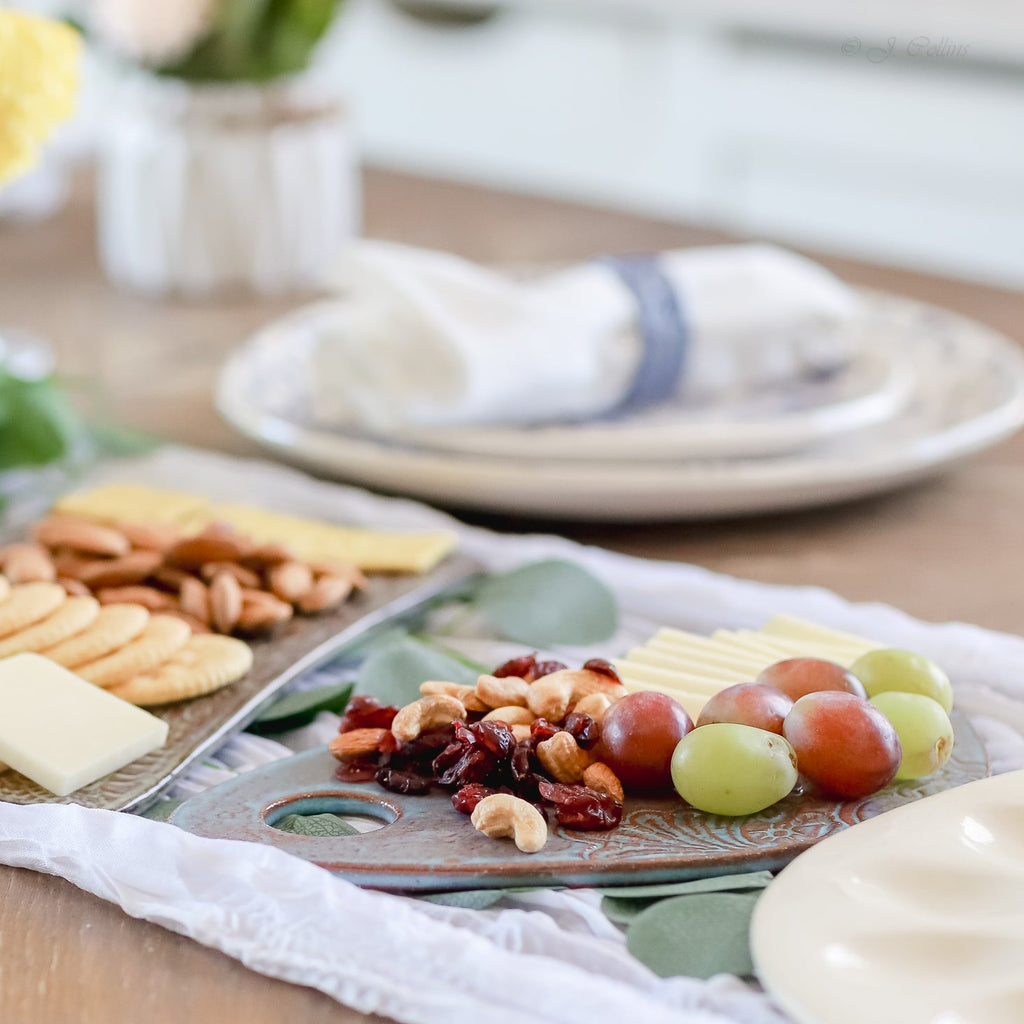 Platter of assorted cheeses, fruits, and nuts on a wooden table.