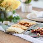 Platter of assorted cheeses and crackers on a wooden table with a decorative background.
