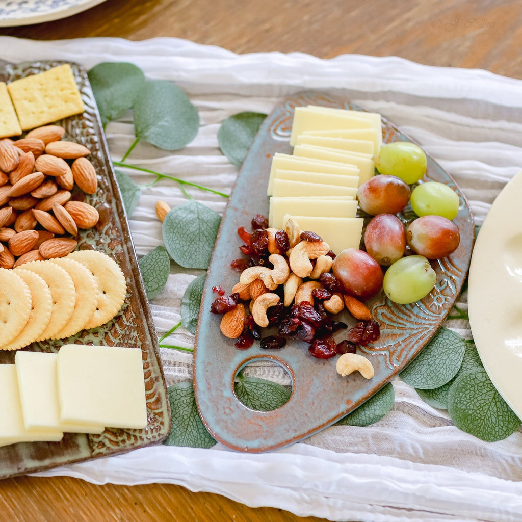 Platter of cheese, crackers, and nuts on a decorative tray with greenery.