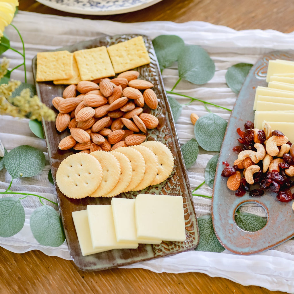 Platter with crackers, almonds, and cheese on a decorative cloth.