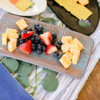 Platter of fruit including strawberries, blueberries, and pineapple chunks on a decorative mat.