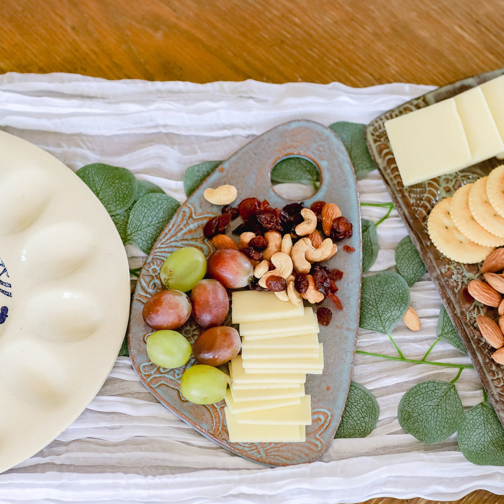 Platter with cheese, grapes, nuts, and crackers on a decorative mat.