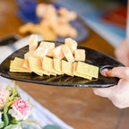 Hand holding a black plate with various types of crackers.
