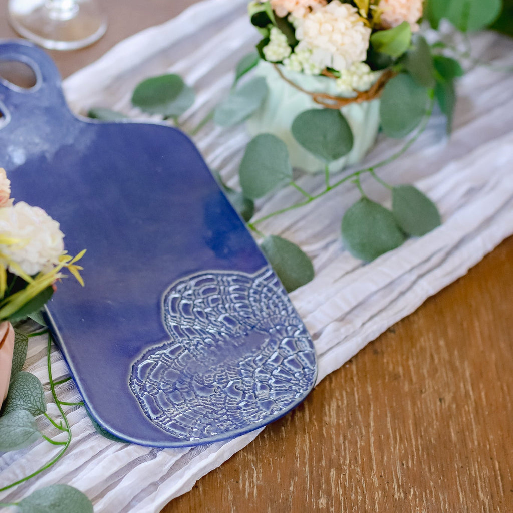 Blue cutting board with floral design on a wooden table