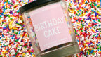 Candle labeled 'Birthday Cake' on a background of colorful sprinkles