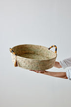 Person holding a woven basket with handles on a light gray background