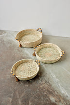 Three woven baskets with handles on a concrete surface
