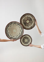 Three woven baskets held by people against a white background