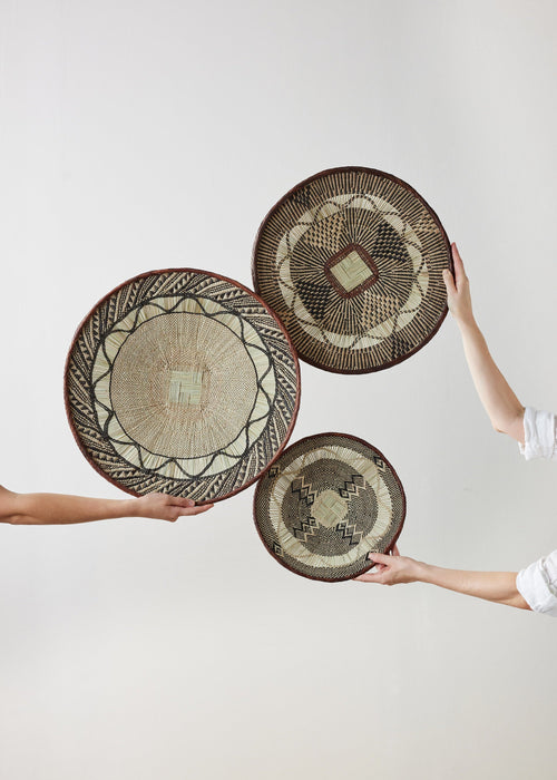 Three woven baskets held by people against a white background