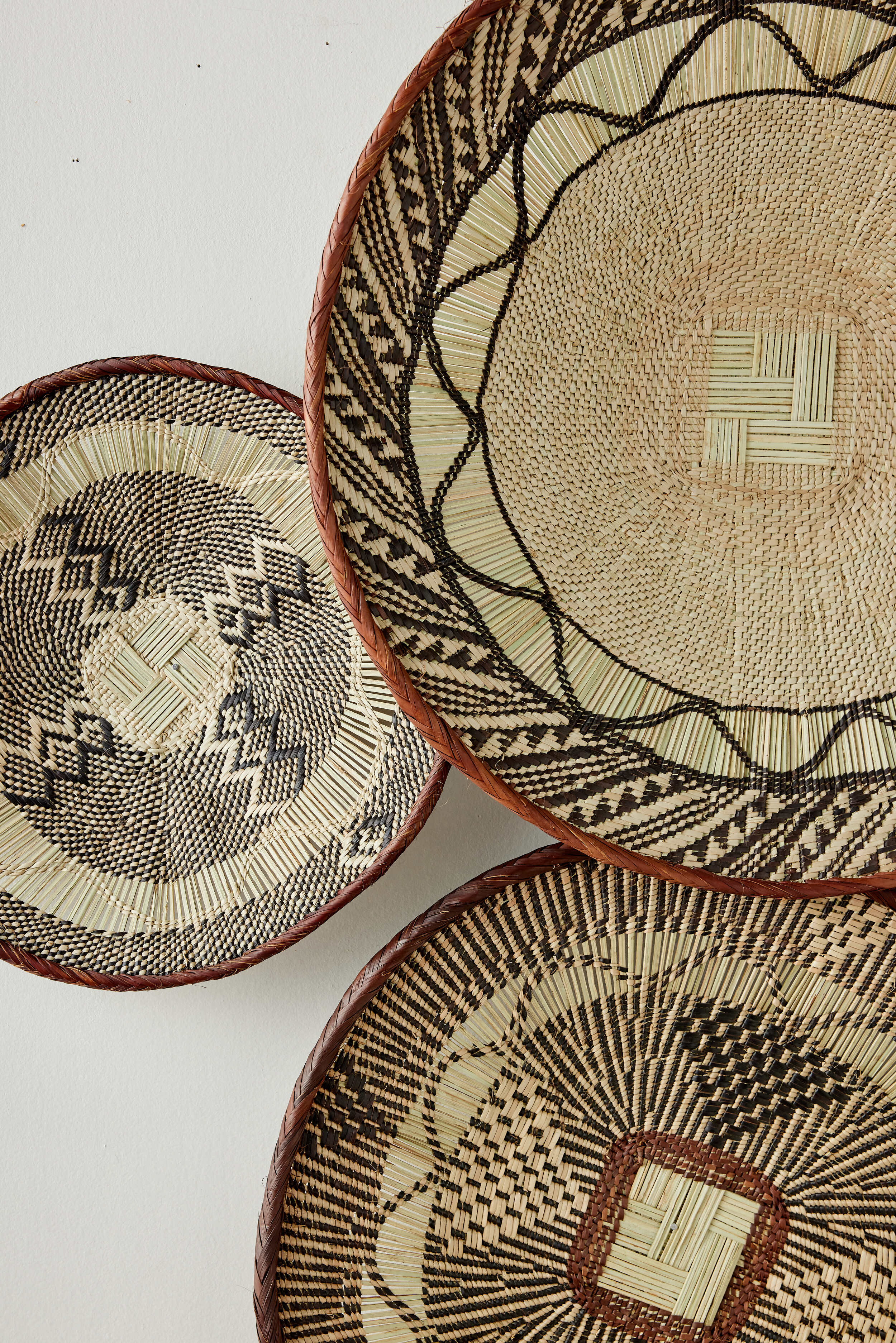 Three woven baskets with geometric patterns on a white background