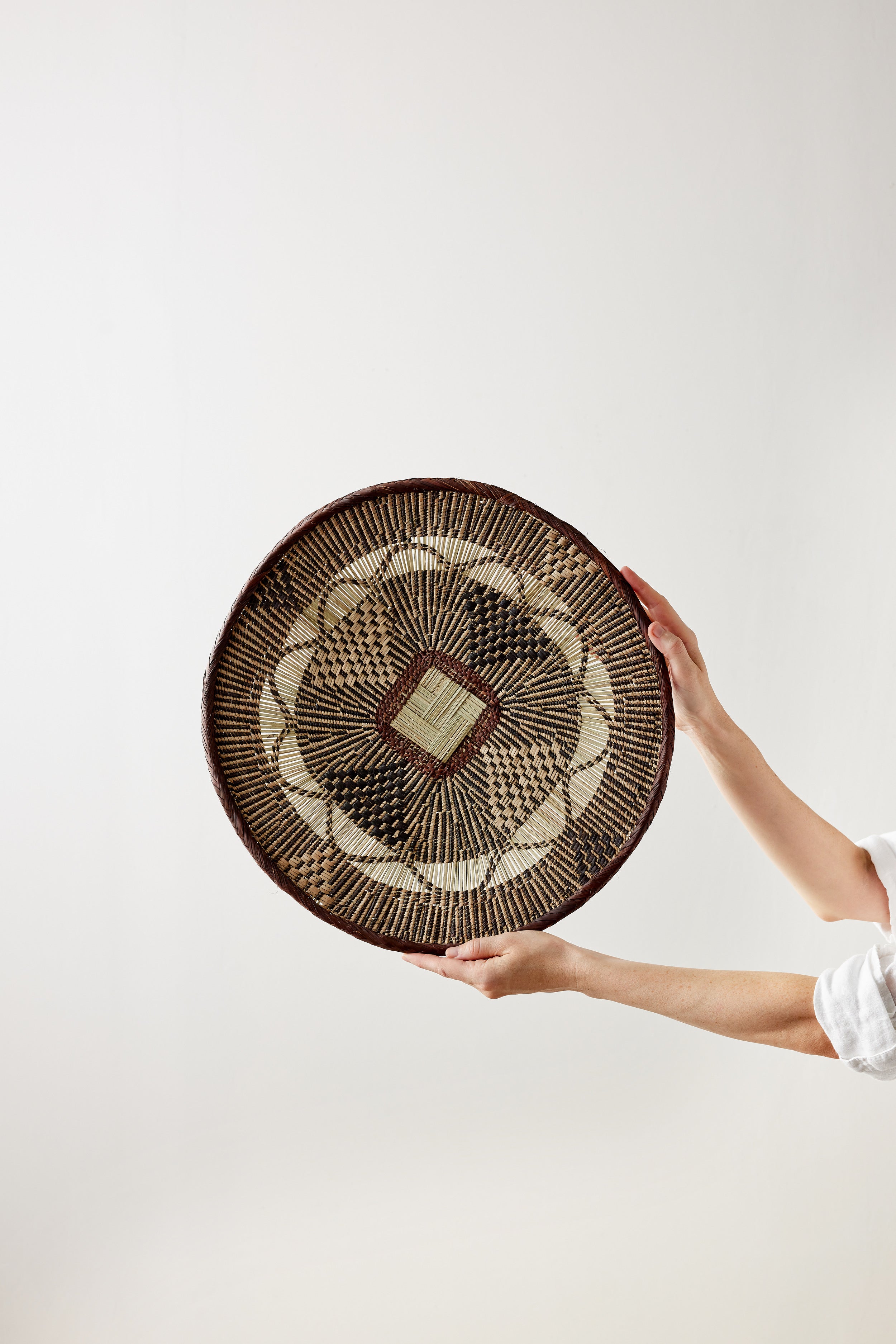 Person holding a woven basket against a white background