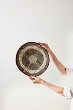 Person holding a woven basket with geometric pattern against a white background