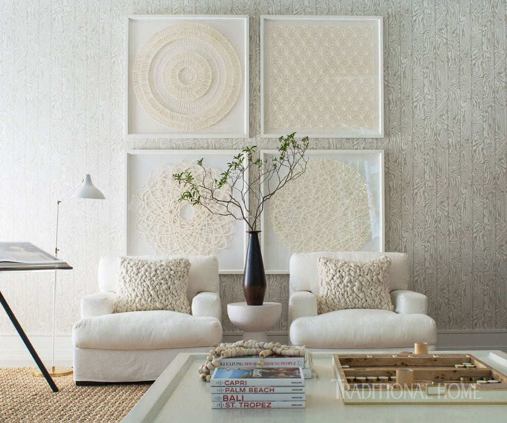 Living room with white furniture, decorative pillows, and framed artwork on a textured wall.