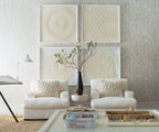Living room with white furniture, decorative pillows, and framed artwork on a textured wall.