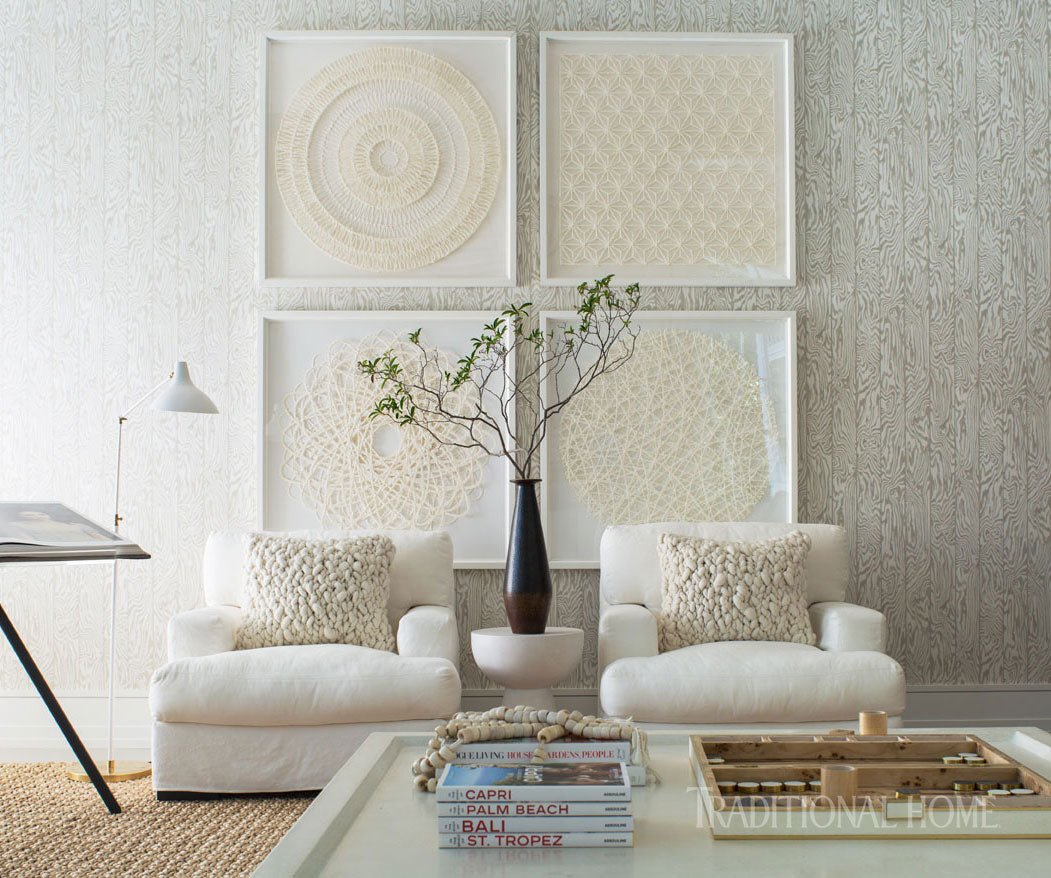 Living room with white furniture, decorative pillows, and framed artwork on a textured wall.