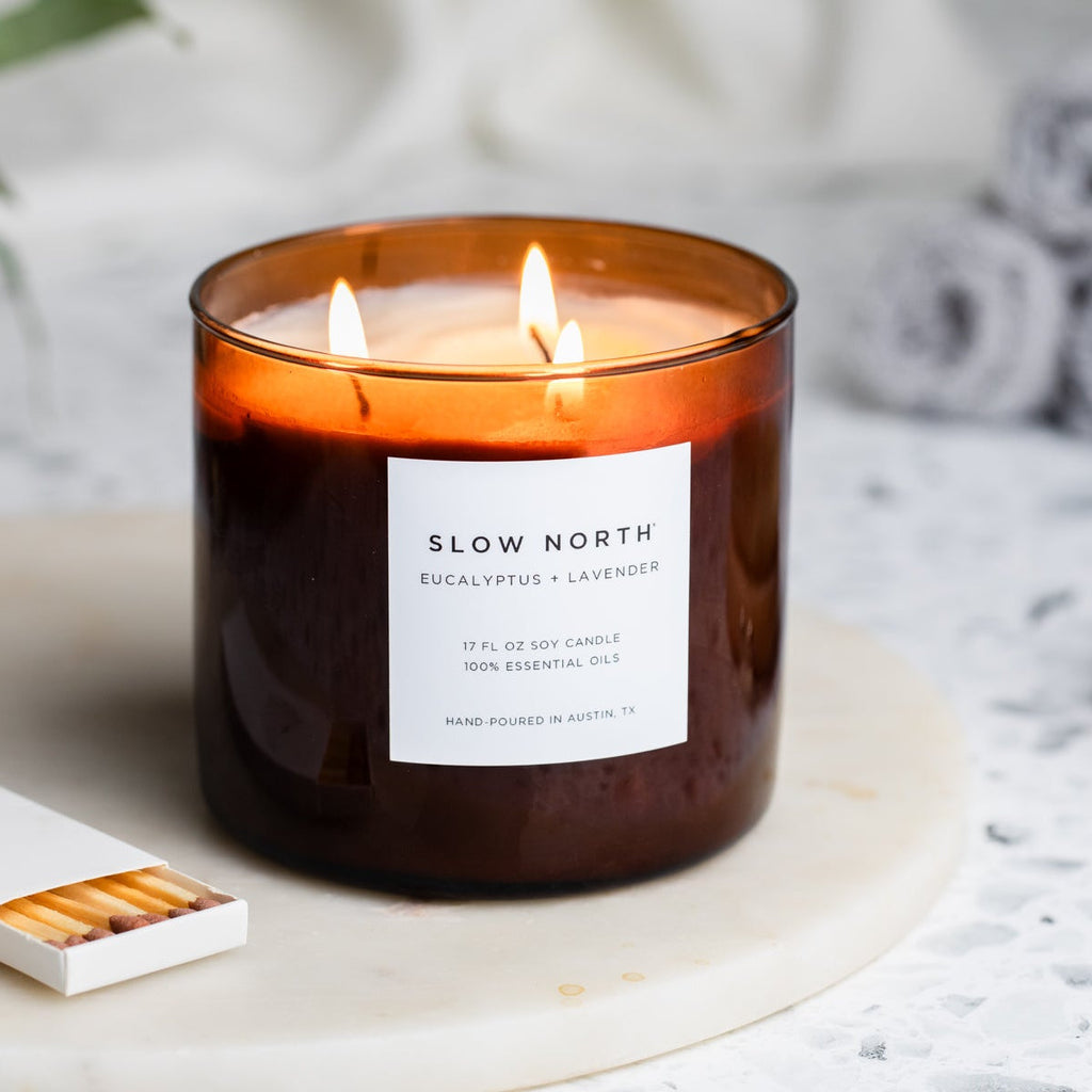 Scented candle with 'Slow North' label on a blurred background