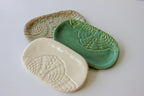 Three ceramic dishes in beige, green, and white with textured patterns on a light gray background.