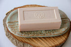 Bar of soap on a decorative ceramic dish on a wooden block