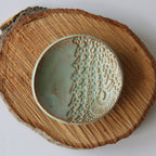 Ceramic ring dish with textured design on a wooden surface