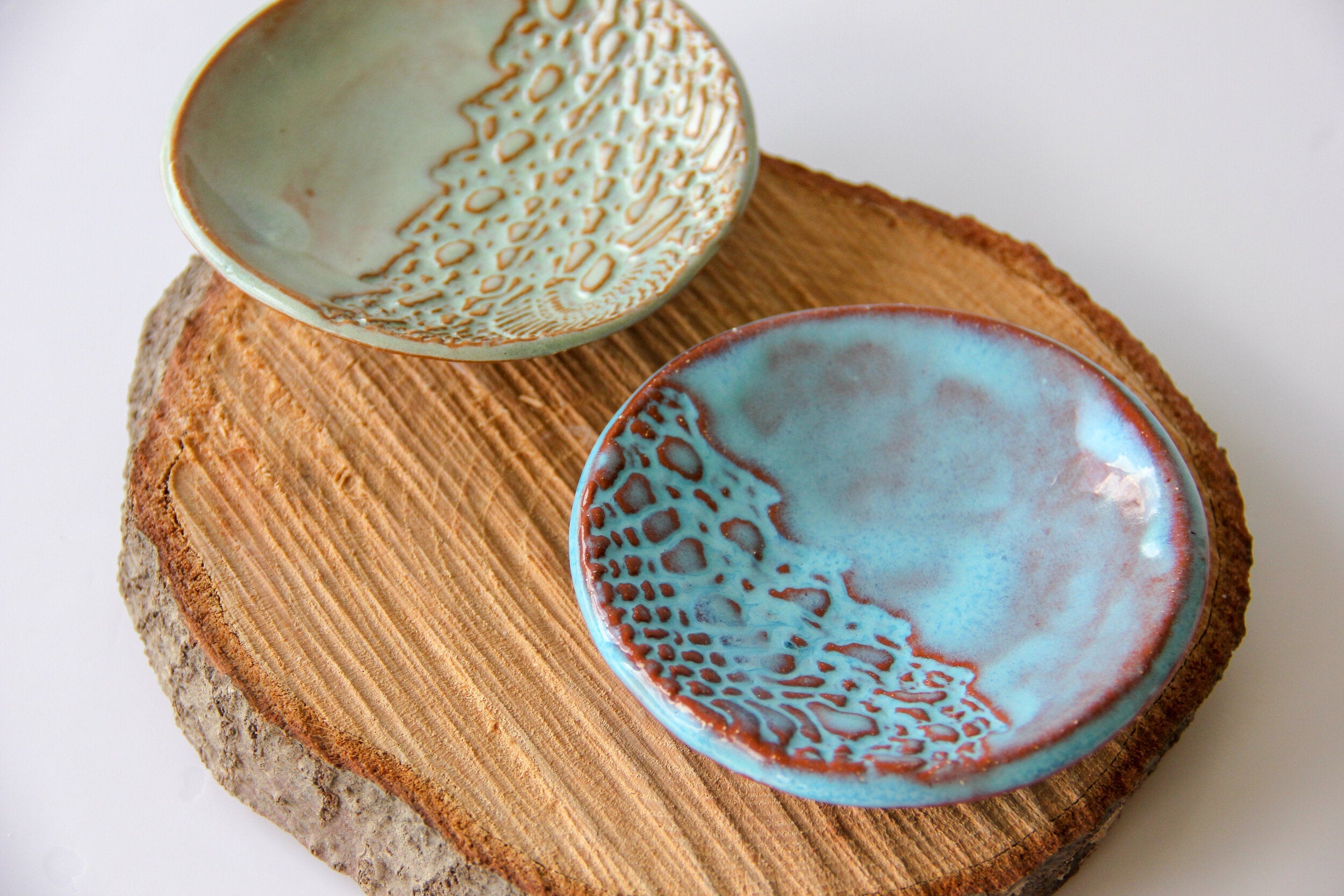 Two ceramic dishes with textured surfaces on a wooden board