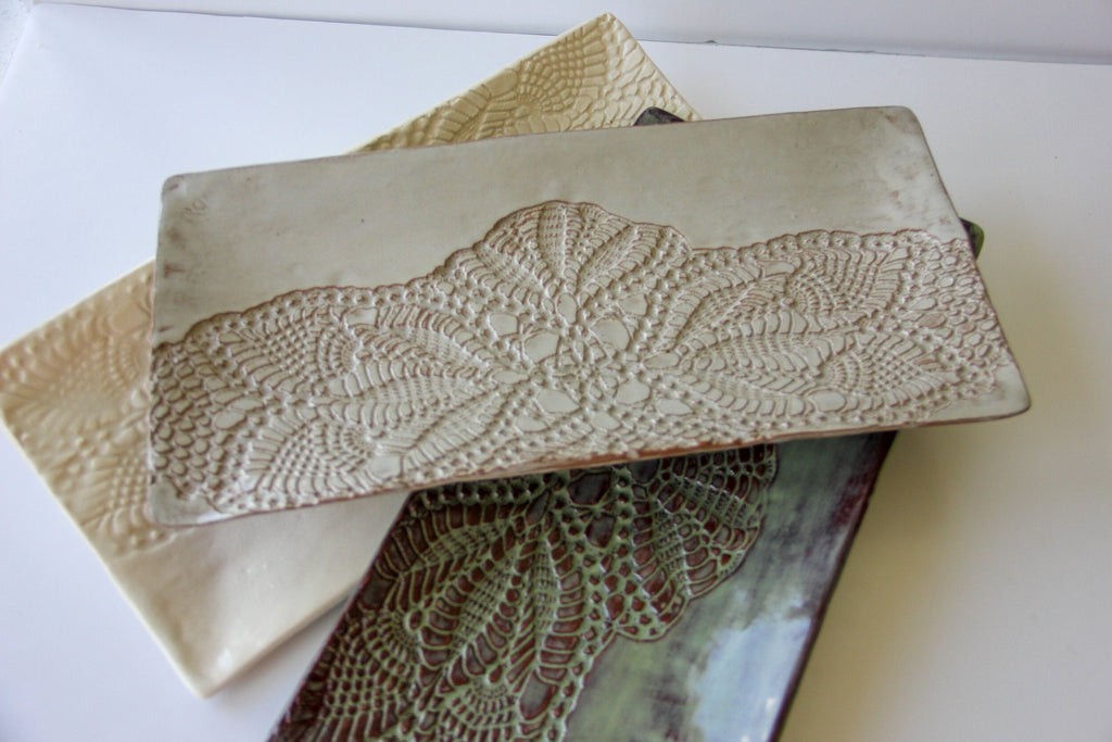 Beige ceramic platter with lace detailing on a white surface