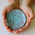 Hands holding a ceramic ring dish with textured surface