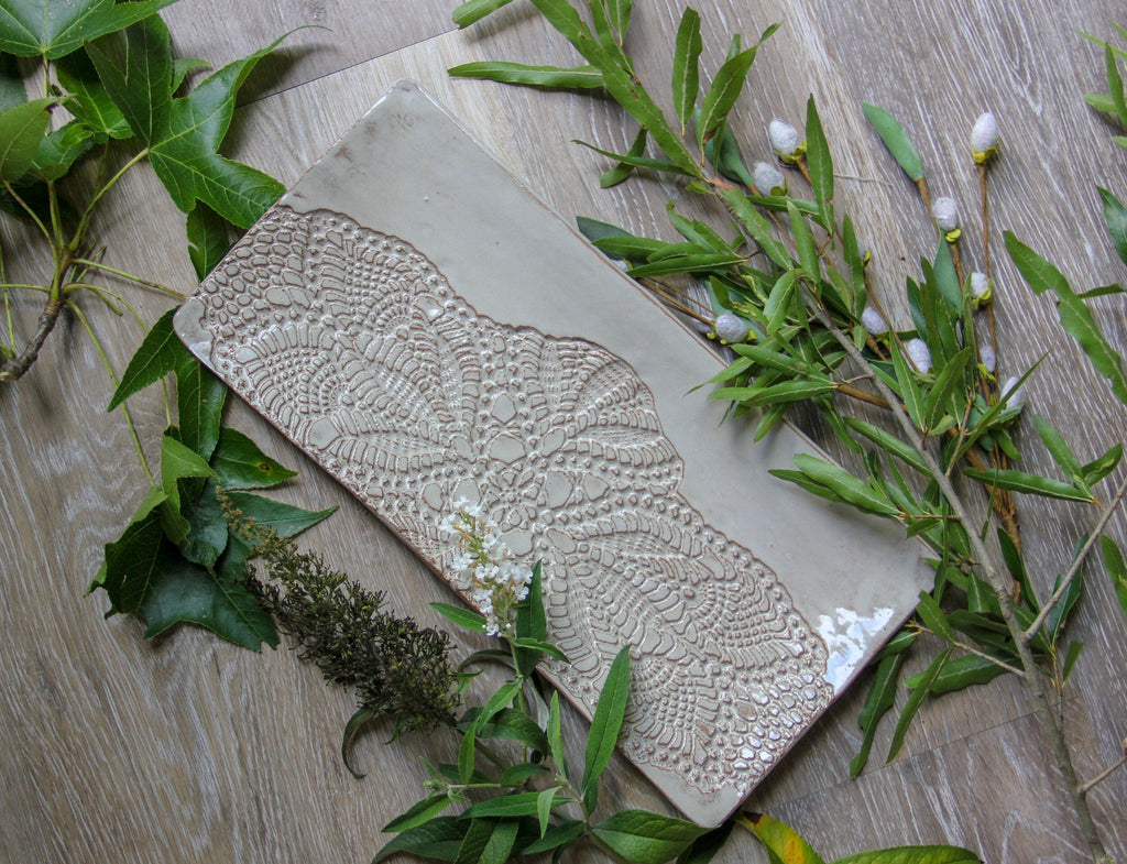 Decorative platter with intricate patterns on a wooden surface with greenery