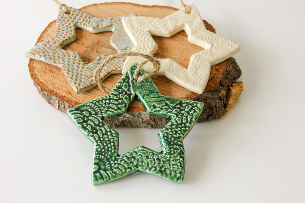 Three ceramic star-shaped ornaments on a wooden block with a white background