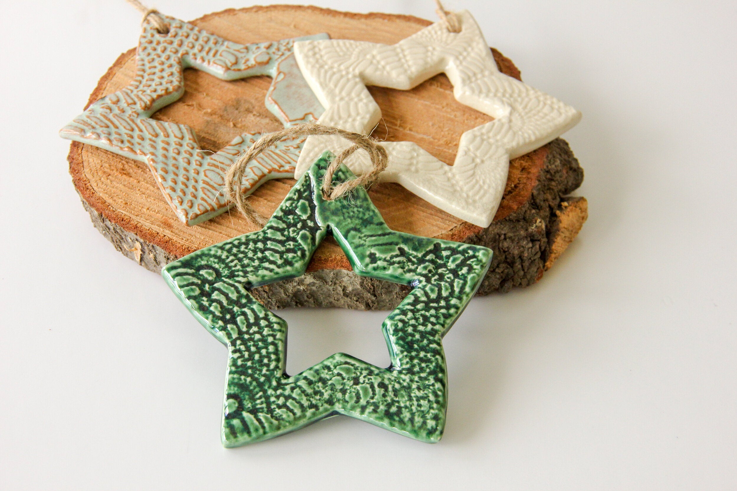 Three ceramic star-shaped ornaments on a wooden block with a white background