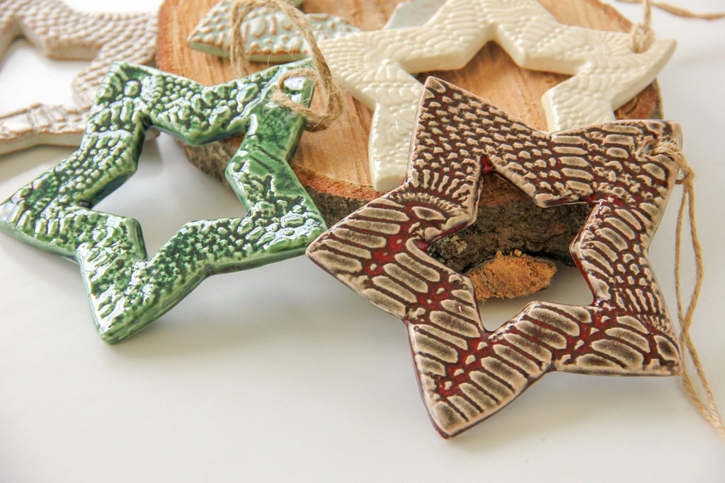 Star-shaped ceramic ornaments in various colors on a white surface