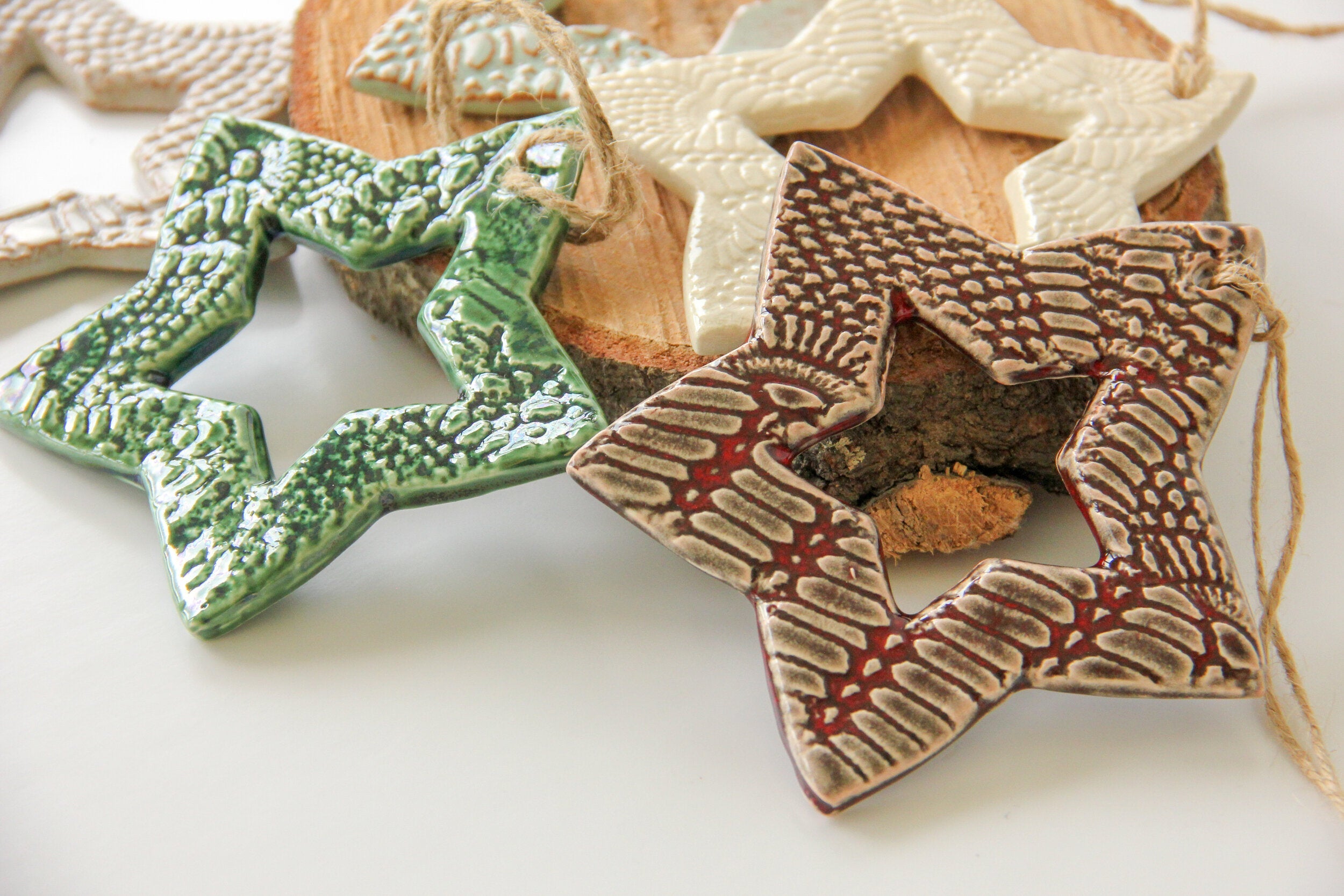 Star-shaped ceramic ornaments in various colors on a white surface