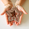 Two hands holding a ceramic star-shaped ornament with a textured surface.