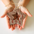 Two hands holding a ceramic star-shaped ornament with a textured surface.