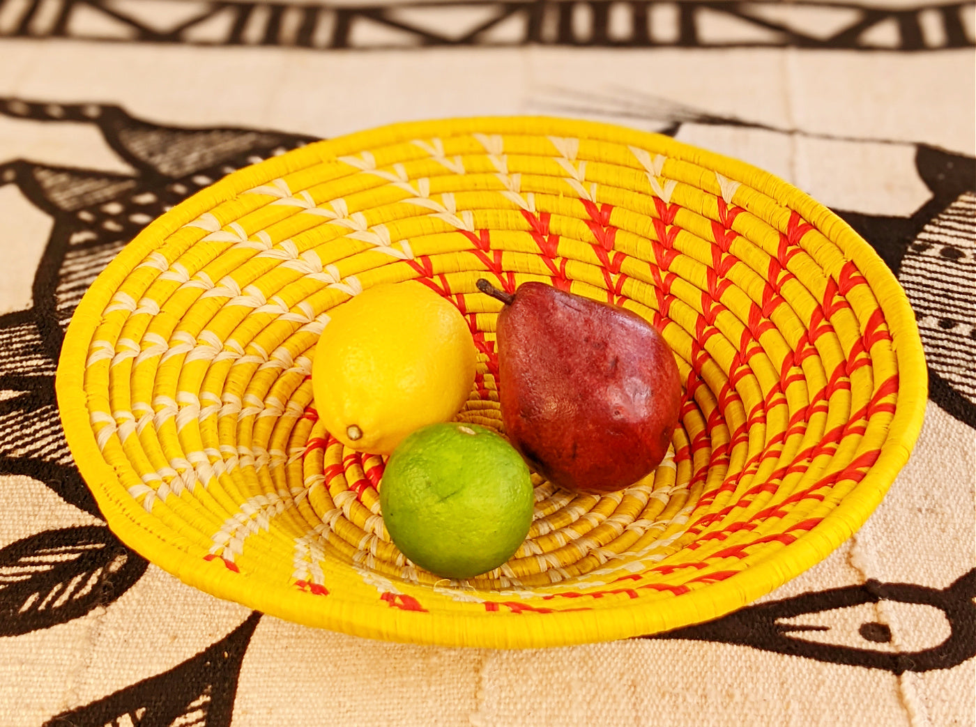 Yellow woven basket with a pear, lemon, and lime on a patterned fabric background