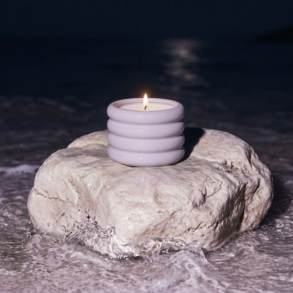 Candle in a holder on a rock by the water at night