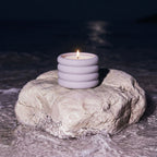 Candle in a holder on a rock by the water at night