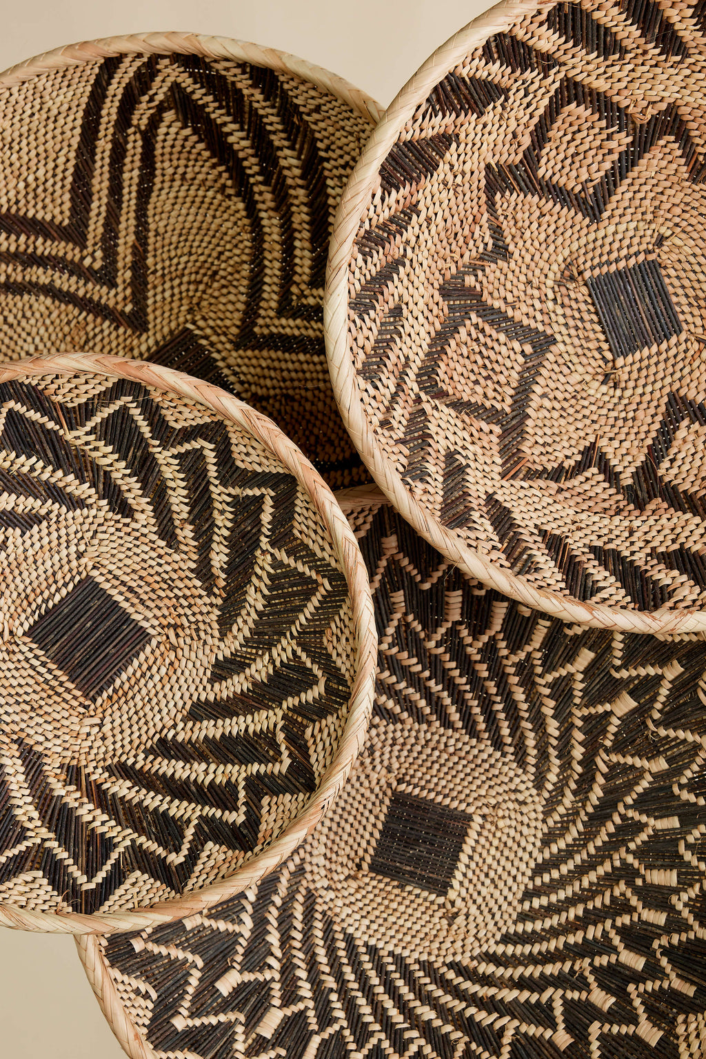 Woven baskets with geometric patterns on a beige background