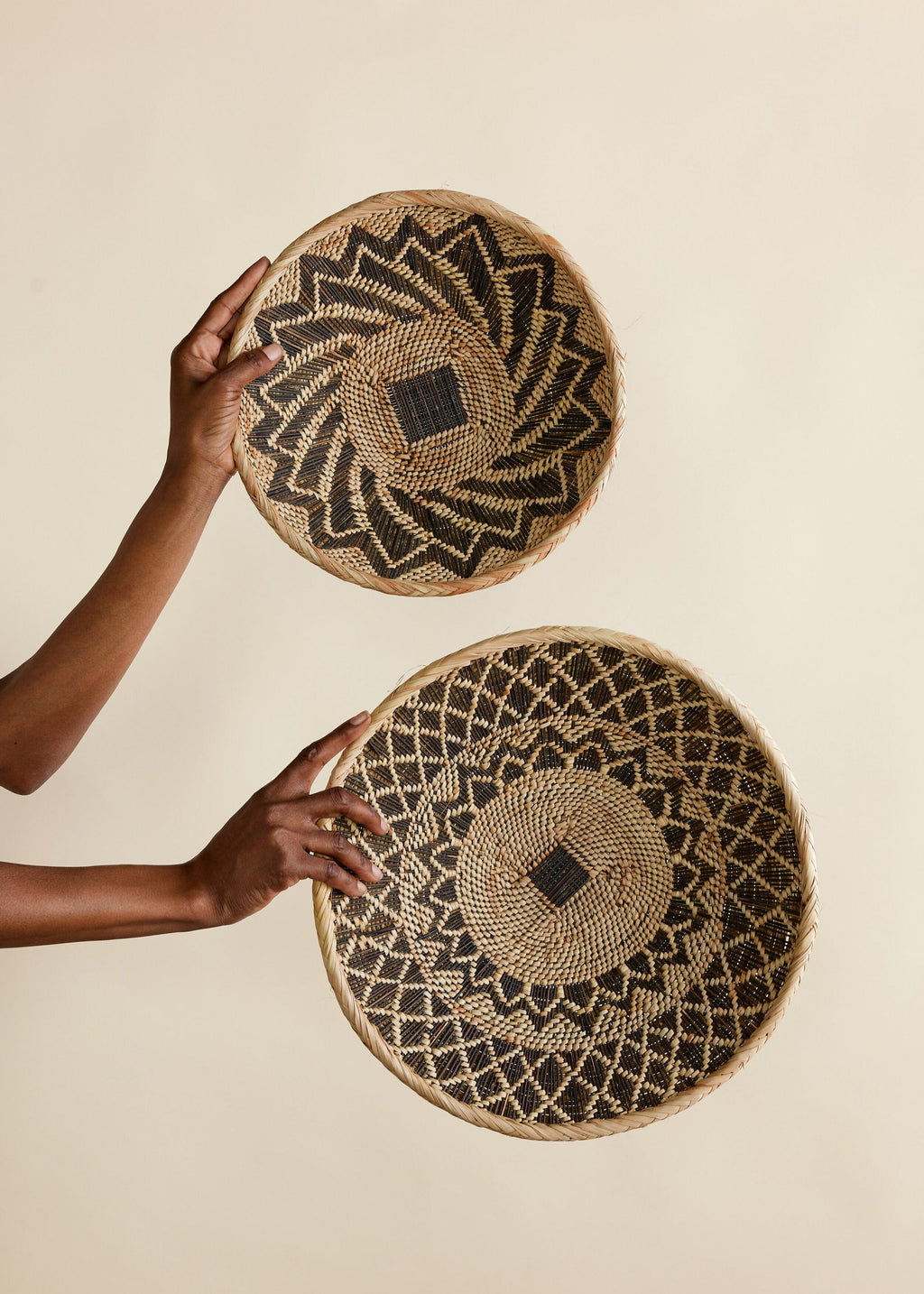 Two woven baskets held by a person against a beige background