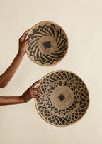 Two woven baskets held by a person against a beige background