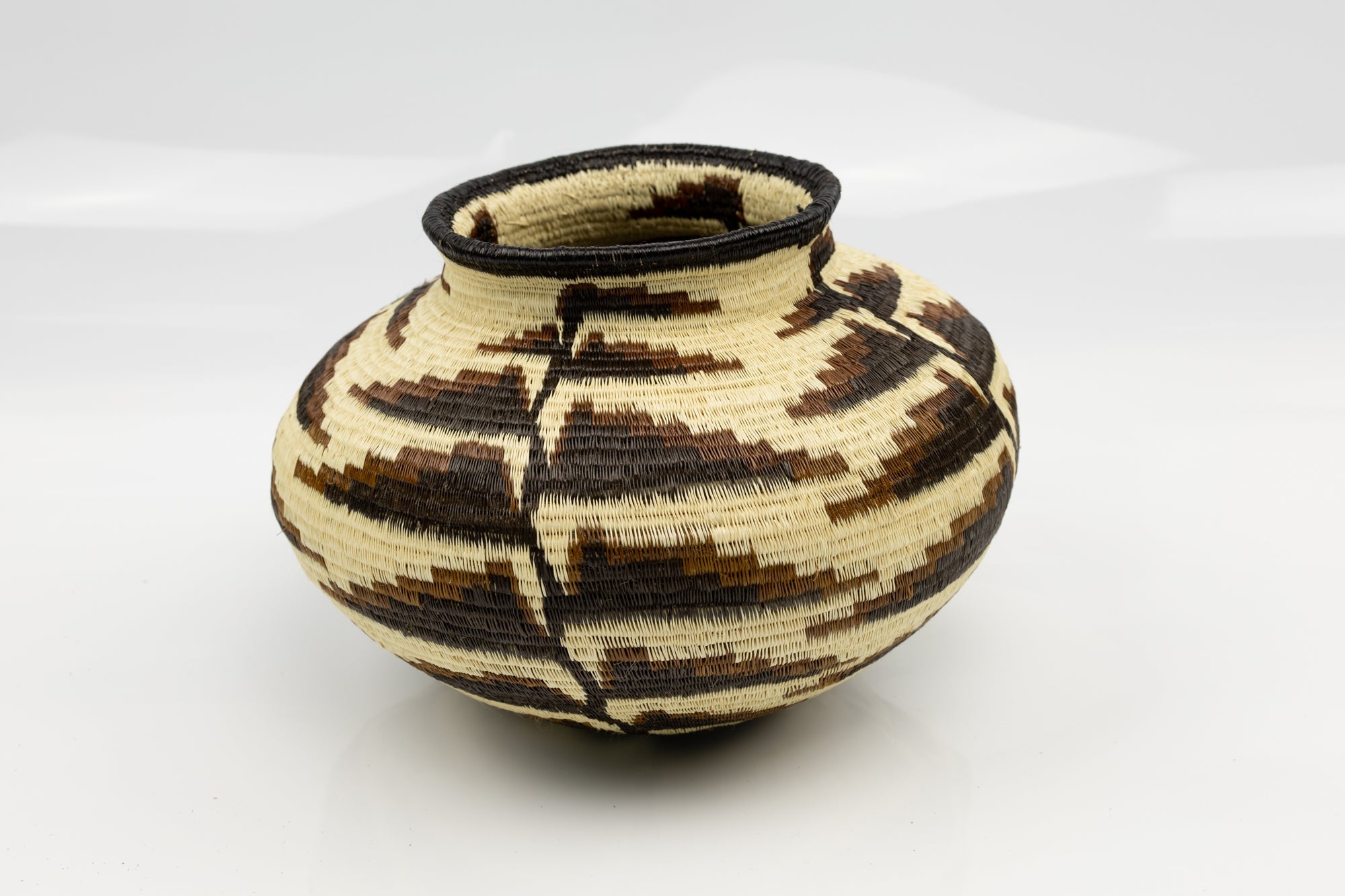 Handcrafted woven basket with geometric pattern on a white background