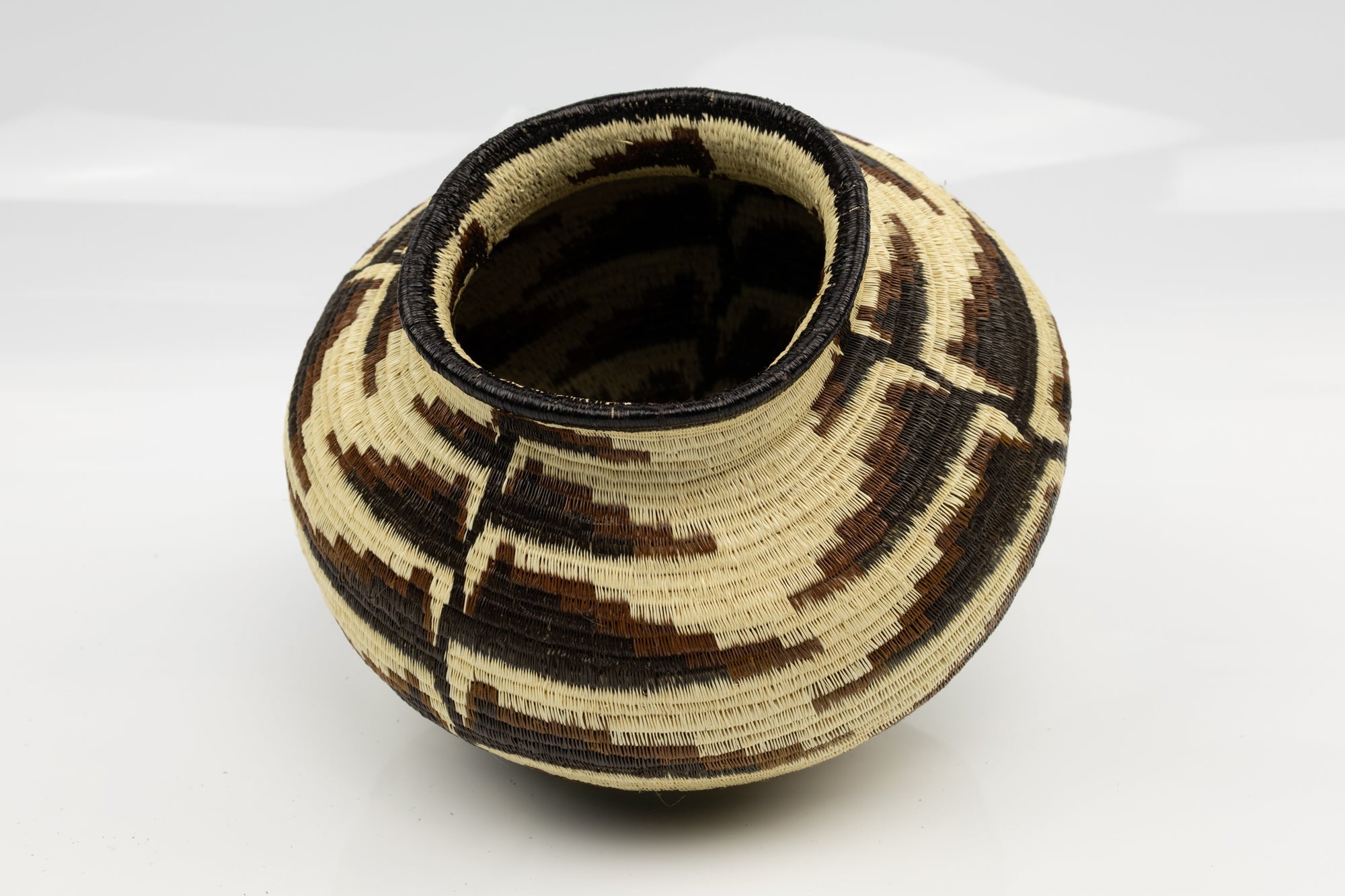 Woven basket with geometric pattern on a white background