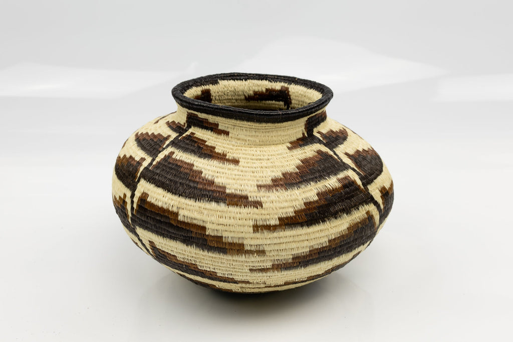 Handwoven basket with black and beige pattern on a white background