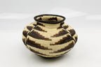 Handwoven basket with black and beige pattern on a white background