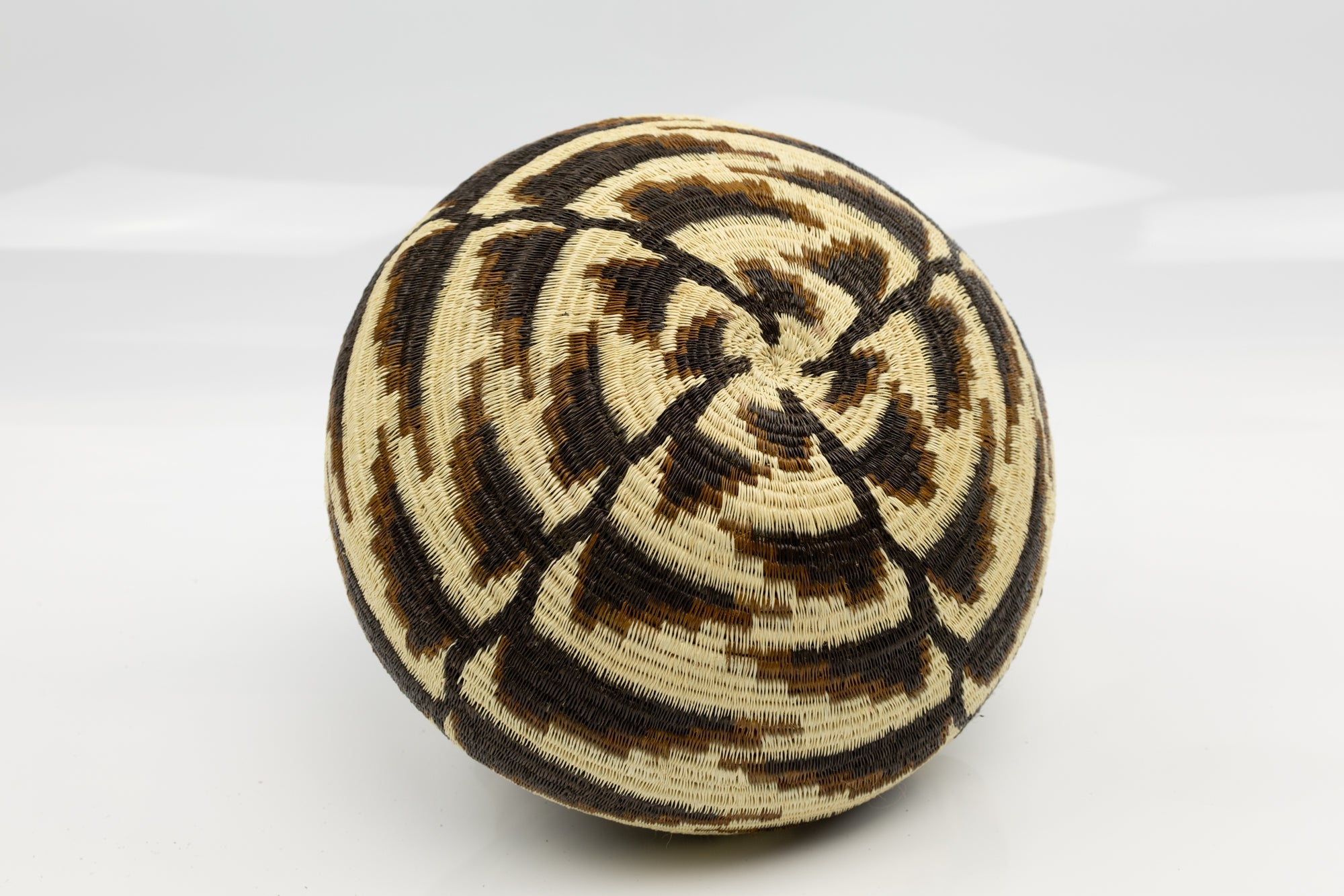 Woven basket with black and beige pattern on a white background