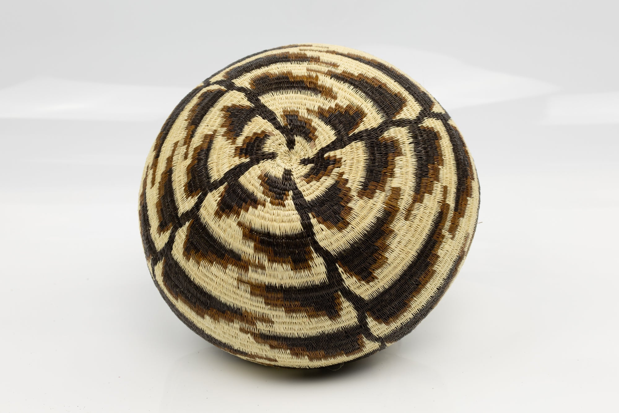 Woven basket with concentric circle pattern on a white background