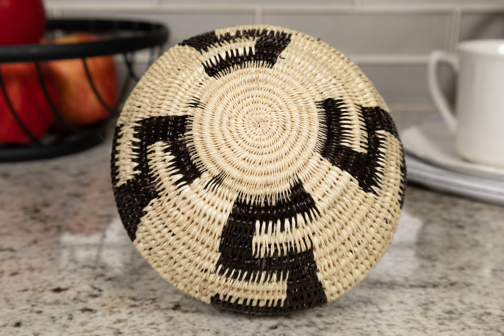 Round woven basket with black and beige pattern on a countertop