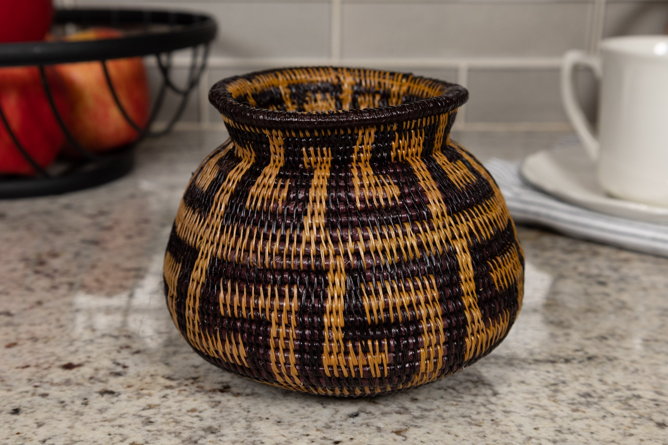 Woven basket with black and brown pattern on a kitchen counter