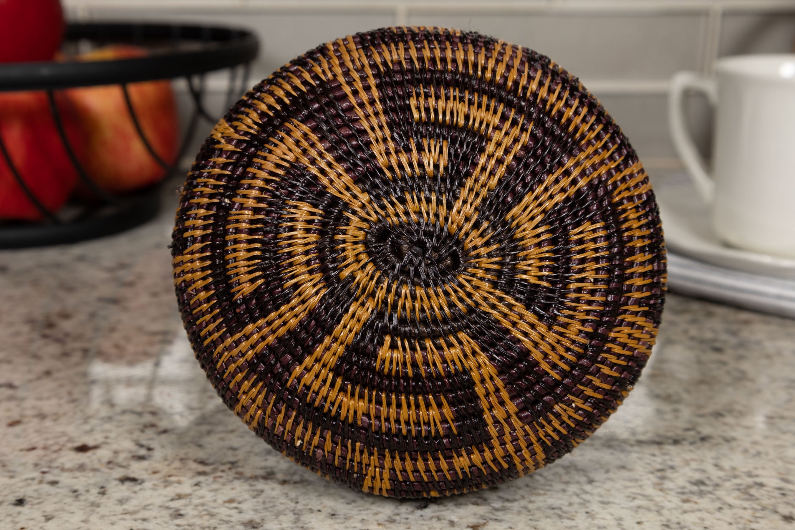 Woven basket bottom with black and brown pattern on a kitchen counter