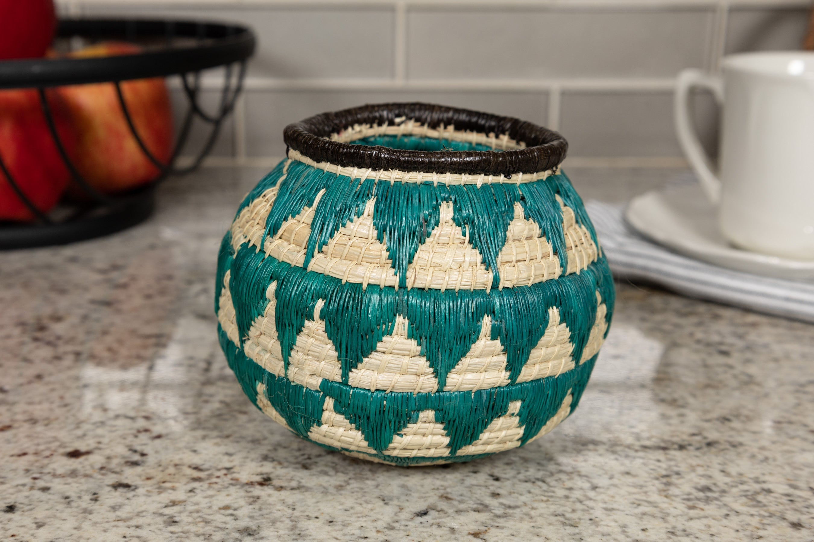 Decorative woven basket with geometric tourquise blue pattern on a kitchen counter
