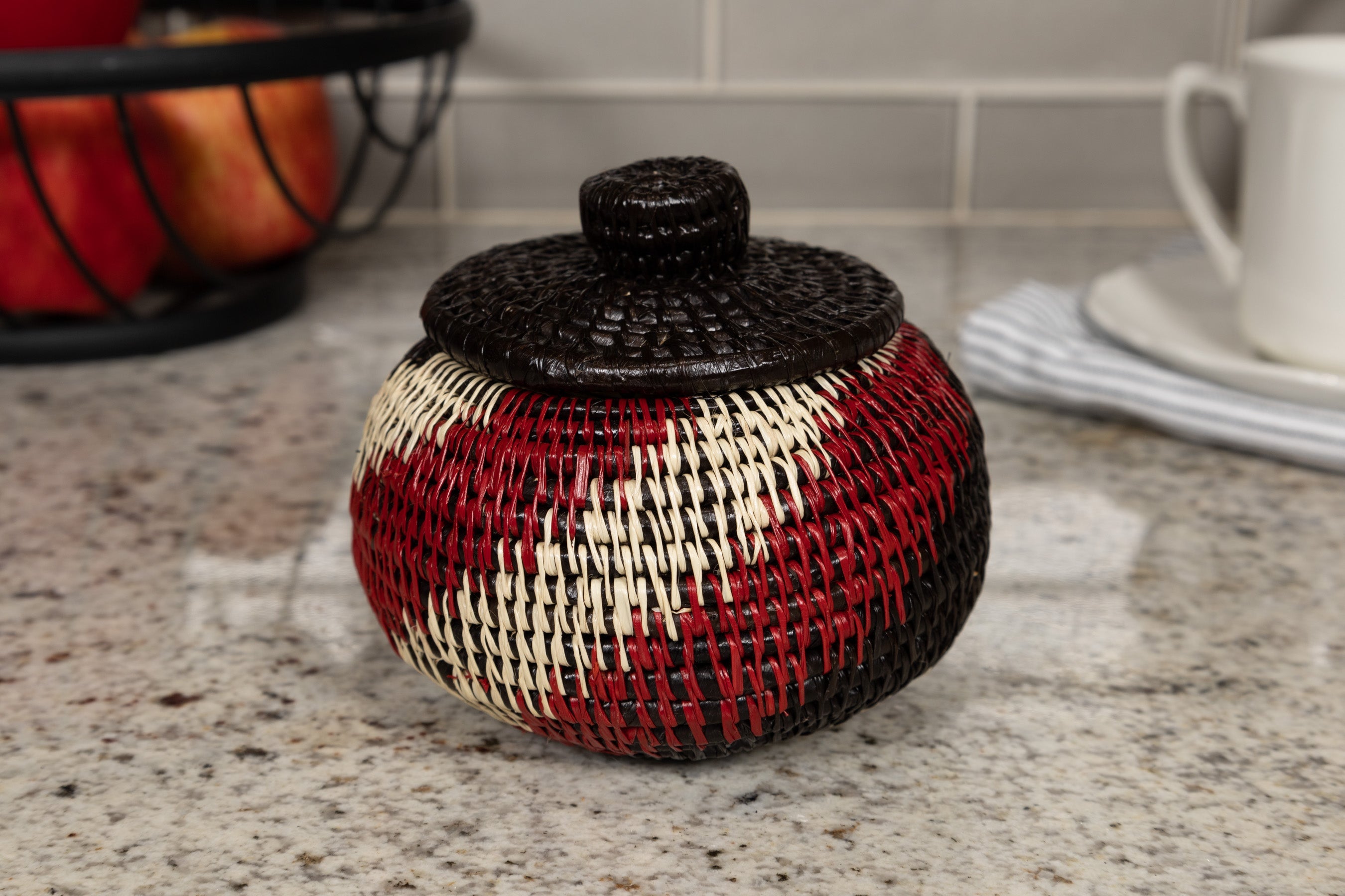 Woven basket with black lid on a kitchen counter